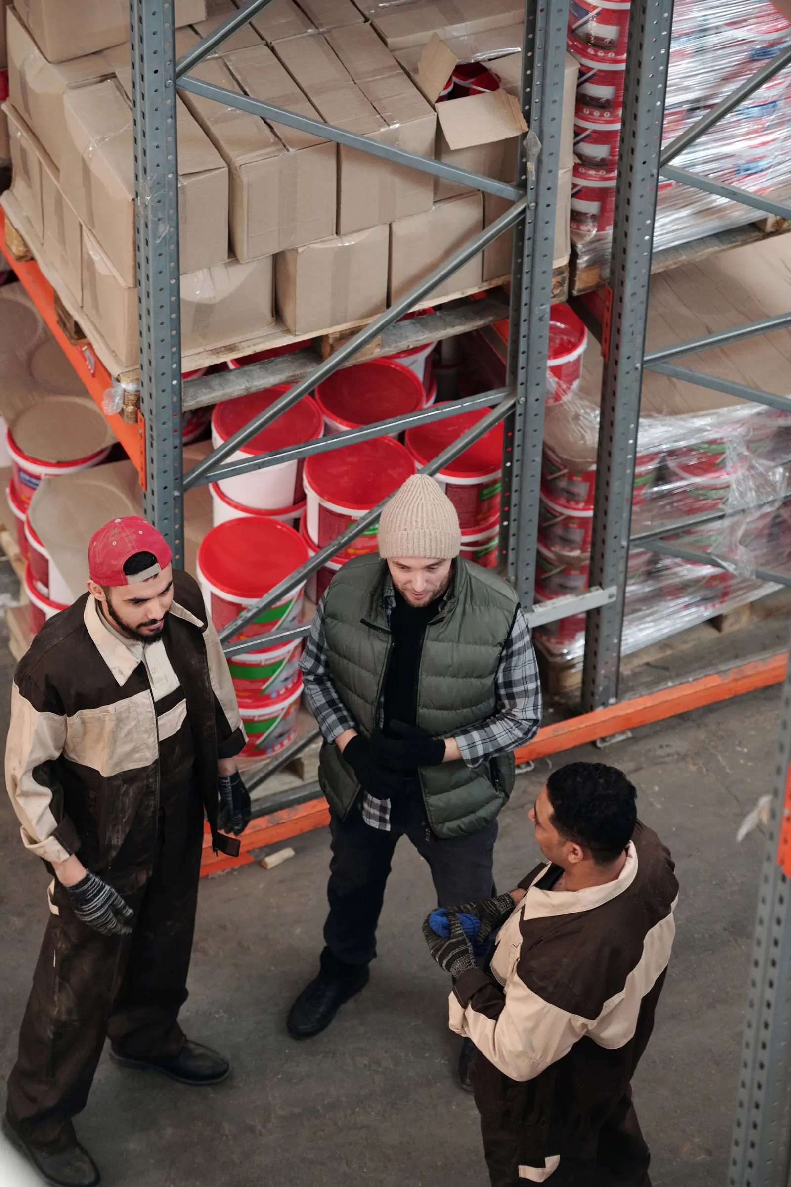 Warehouse staff discussing an order between rows of stocked shelves