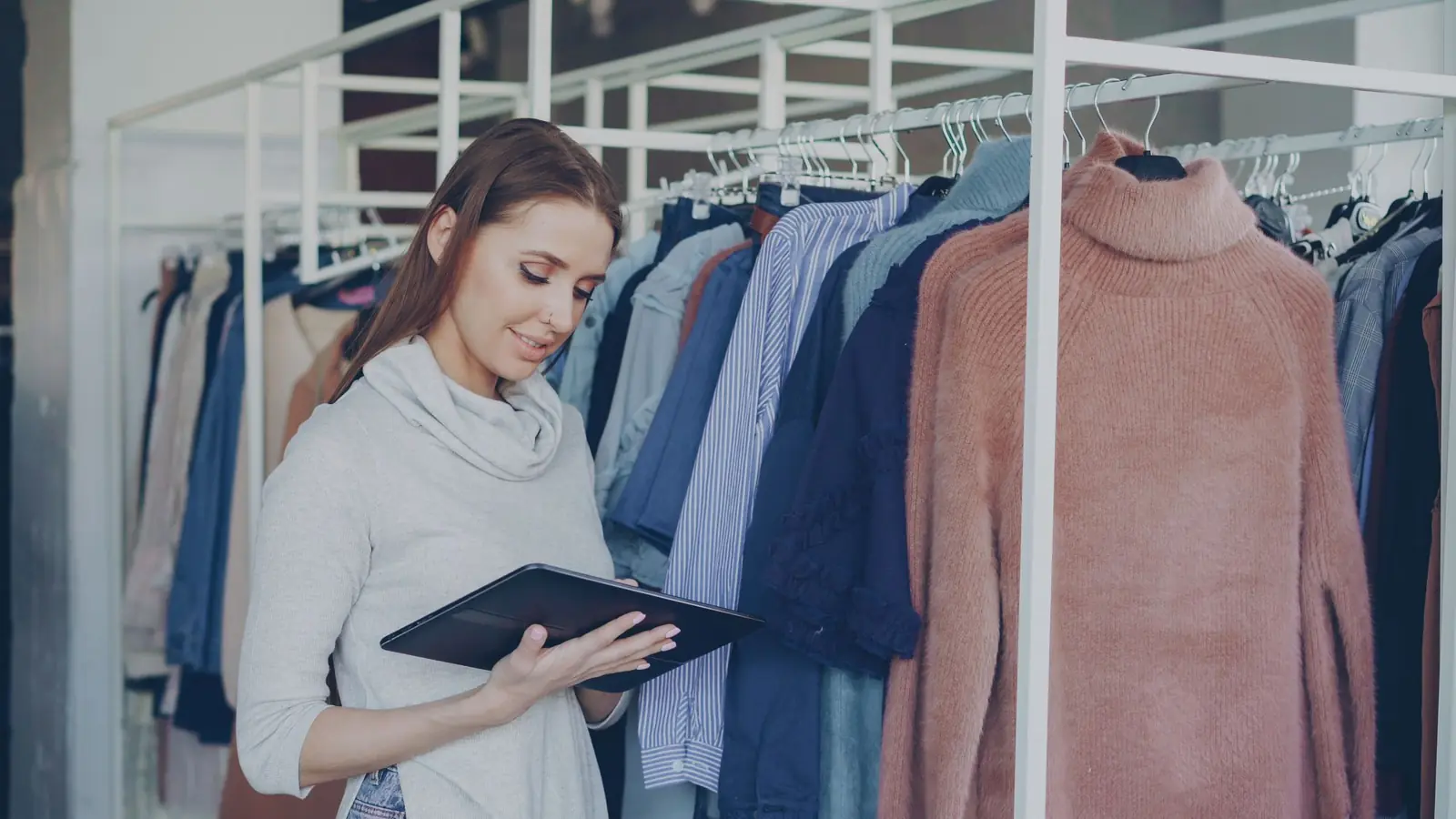 A store associate checking inventory on a tablet in a clothing store