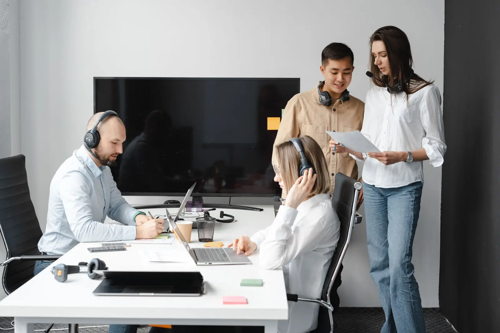 Recruitment coordinators with headsets working at laptops in a bright office
